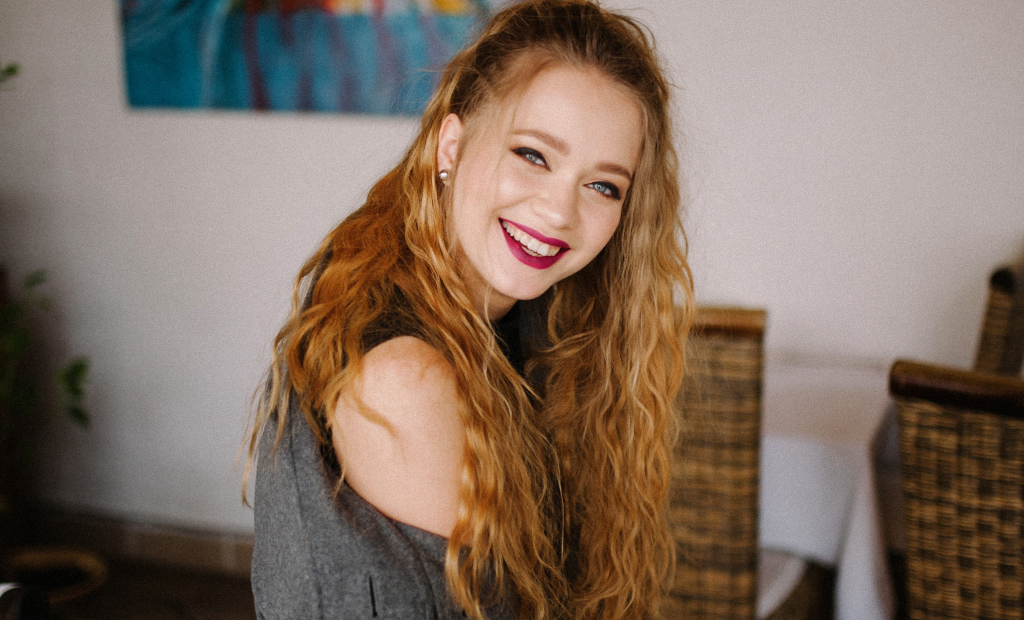 woman with a blonde curly hair is wearing dark pink lipstick