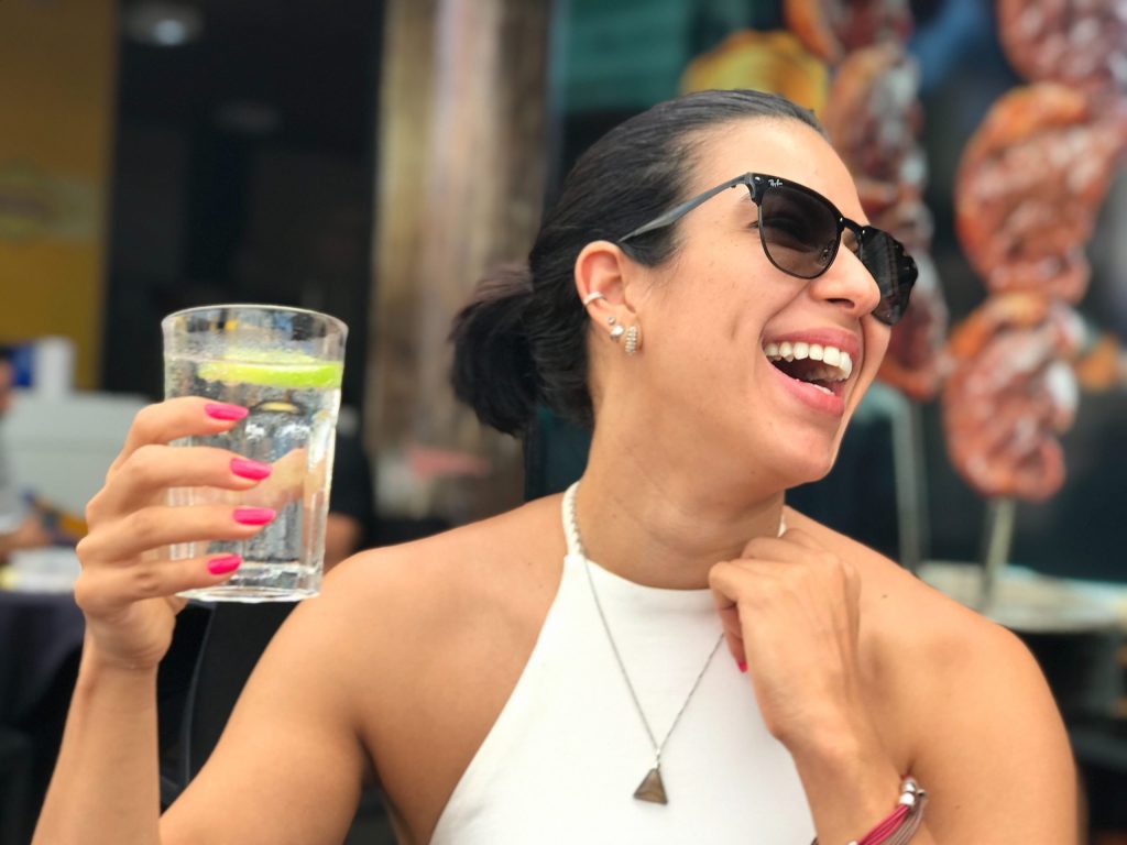 a happy woman with sunglasses is holding a glass of water