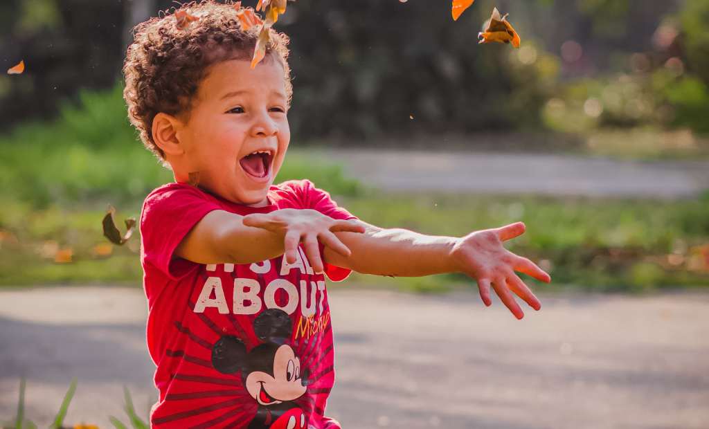 a kid wearing a red shirt is playing with leaves