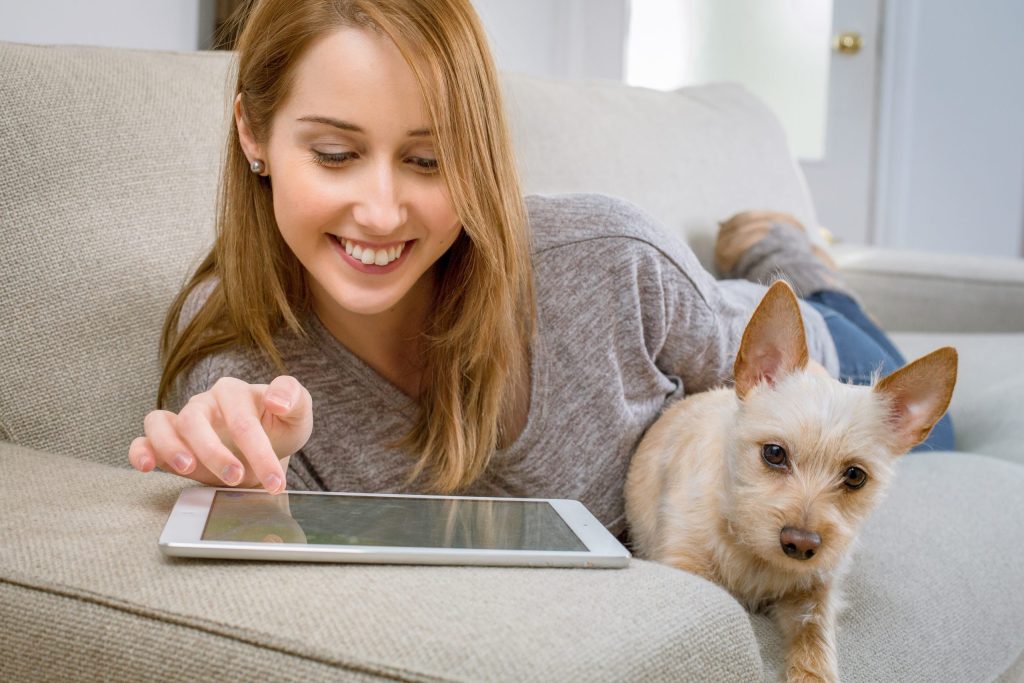 a woman browsing through her tablet with her dog