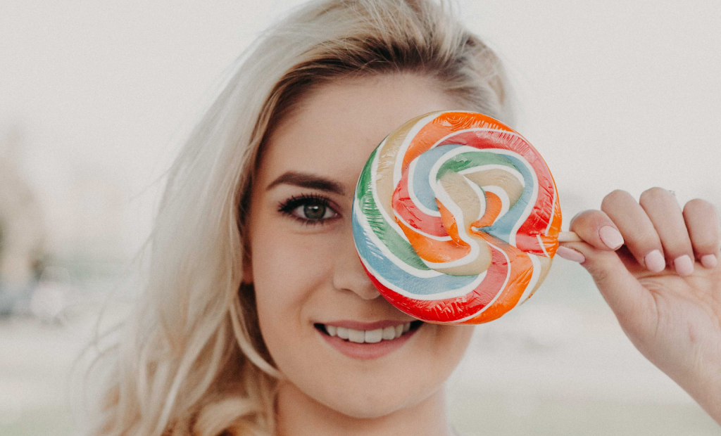 a sweet woman holding a big candy placing to her cheeks