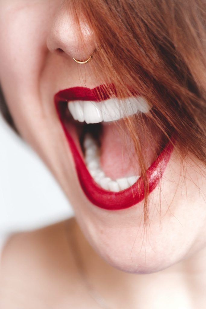 woman with nose piercing is wearing a red lipstick