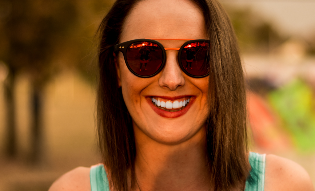 woman with sunglasses is showing off her white teeth