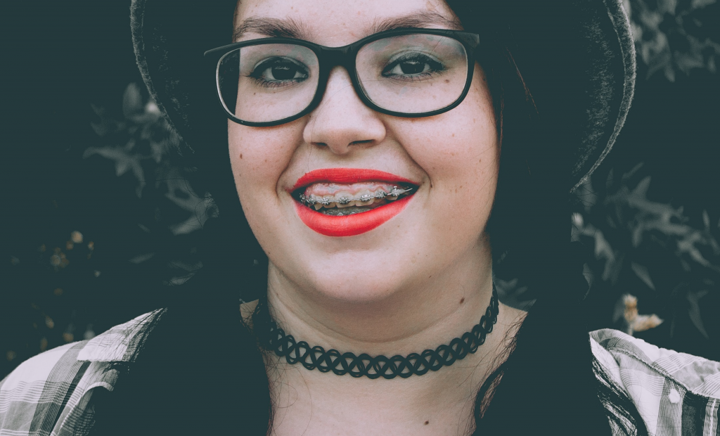 a woman with glasses exposing her smile with braces