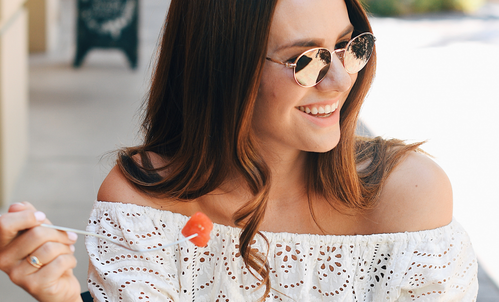 a happy woman with sunglasses is wearing a white lace off shoulder