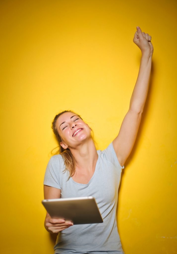 woman on a yellow background is holding an ipad