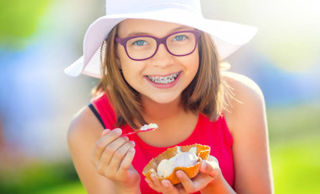 a girl with white summer hat is eating an ice cream