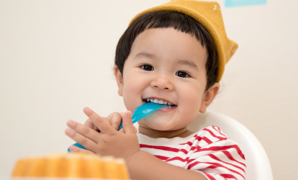 a toddler biting a rubber fork